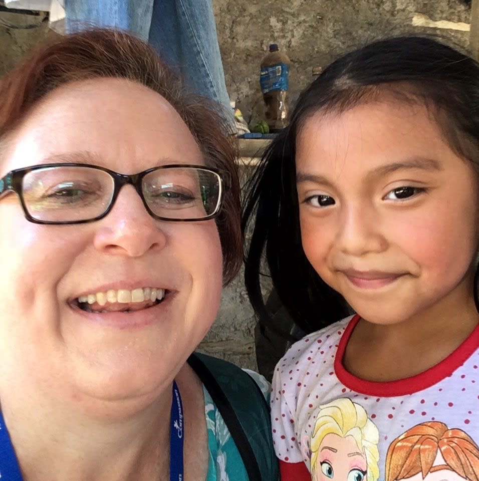 A woman in glasses and a young girl smile at the camera